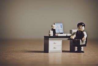 Image depicting a stressed out LEGO man sitting at his desk