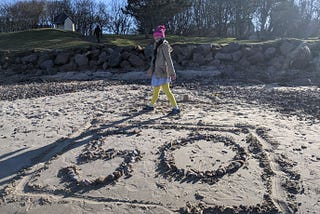 Suzi Mapes, the author’s daughter, on the beach infront of a number 50 made out of pebbles.