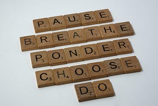 Wooden tiles spelling out the words pause, breathe, ponder, choose, do.