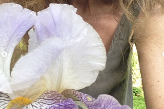 iris blossom in front of woman in sleeveless green shirt