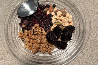 A mixture of walnuts, almonds, peanuts, pistachios, prunes and blueberries, ready to add chia seeds and skim milk.