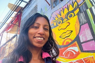 Bukht smiling in front of Mexican street art.