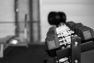 Aligned dumbbells on a rack in a gym.