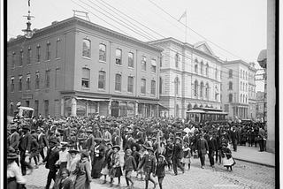 Photograph shows an Emancipation Day parade on Main Street, Richmond, Virginia. The building in the back is 1000 Main Street.
