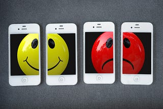 A happy and an unhappy smiley face, shown on a set of smartphone displays.