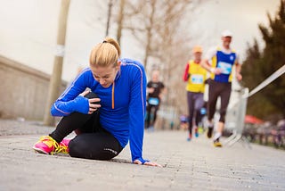 A woman runner on the ground, holding her knee.