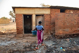 A Malawian woman makes her way through a cluttered pathway on her way to a inadequate toilet facility at a health center.