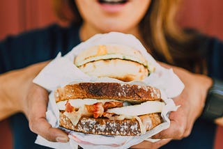 photo of women holding large sandwich up to eat