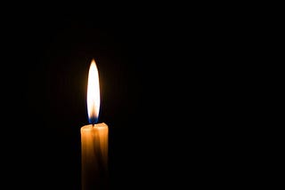 One lit candle with a solid black background
