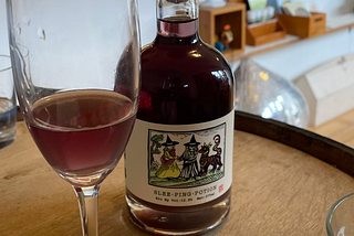 A bottle of Mānoa Honey’s Slee-Ping-Potion Mead behind a glass half-full.