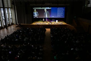 foto de um auditório cheio enquanto Karmen Franinovic e Thomas Link fazem a abertura do evento no palco