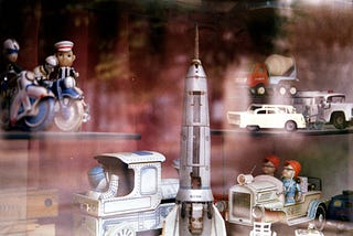 Collection of vintage toys in shop window with classic style toy rocket in the foreground