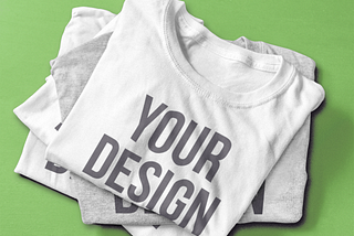 Image of a product mockup used for print on demand business, showing a stack of shirts with the print “your design”.