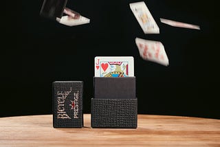 Jack of Hearts poking out of the top of a Bicycle Prestige brand deck of cards with other cards falling blurred in background.