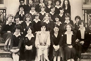 A black and white photo of students with their teacher sitting on the front steps of Varndean High School in 1981. The students are wearing school uniform.