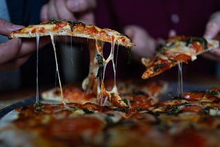 Close up image of a slices of pizza being lifted
