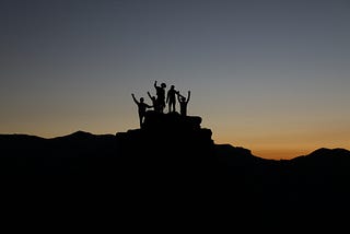 Picture of a group of people, a team, celebrating in the top of a mountain