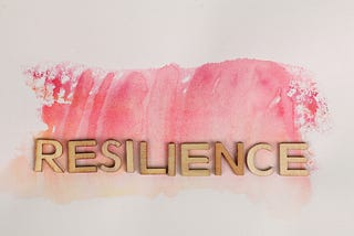 the word Resilience spelled out in gold letters with pink water mark in the background