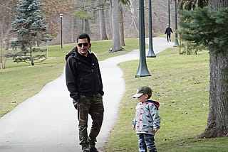 man and small boy standing in park
