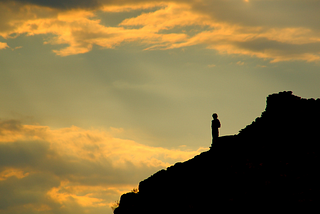 A man looking out, over a mountain peak