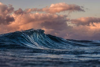 A wave and orange-looking clouds above it.