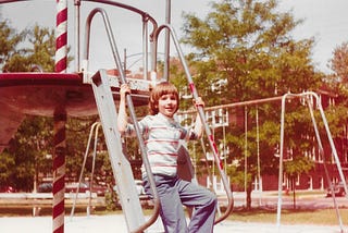 kid in striped shirt, bowl-cut hair, sitting on steps to playground equipment