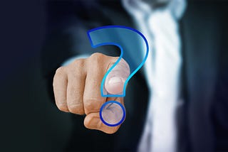 A person pointing a finger into a blue question mark