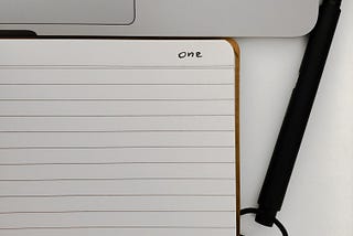 A note book where the word ‘One’ is written in the corner.