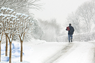 Man on a meditative walk in gentle winter snow contemplating the meainngs of winter and life