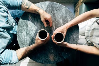 man and woman having coffee at a table