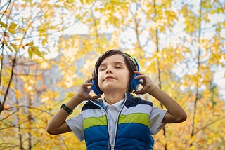 child listening to music through headphones with eyes closed