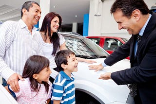 A salesperson addressing a family at a car showroom