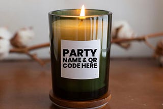A votive candle in a small glass container with a white label sticker on the front that reads “PARTY NAME & QR CODE HERE”