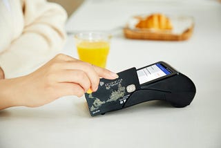 A hand sliding a credit card through a reader.
