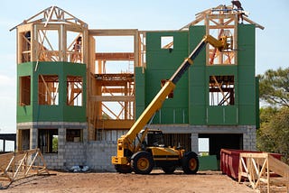 A house under construction with a crane and workers on the roof.