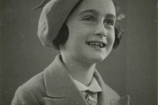 Photo of Anne Frank in 1937, smiling in a hat