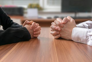 Hands coming together at a work desk to negotiate