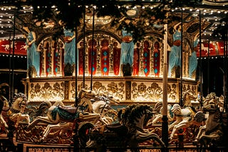 A lighted carousel ride with elaborate designs and painted ponies.