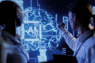 Two professionals analyzing a digital holographic brain with AI text overlay, representing artificial intelligence and data-driven innovation in manufacturing.