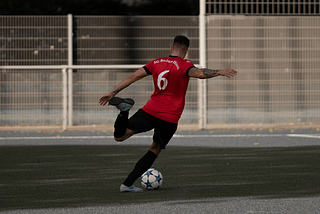 Footballer in a red shirt kicking a ball