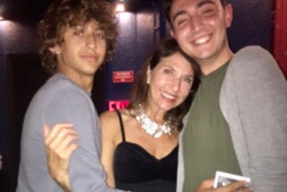 Woman dressed up with teenage sons hugging her posing for a photo.