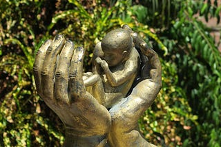 Sculpture of hands holding a newborn