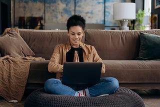 women sitting in the floor close to a brown sofa.