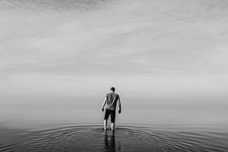 man wading into seemingly endless sea and sky. reason is the true opposite of fear