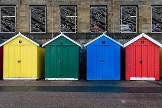 A photo of four wooden booths, each with different colour.
