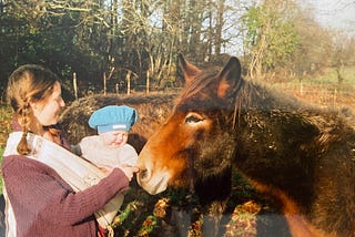 Me with my daughter in a sling stroking the nose of a mule.