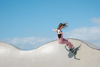 Young woman skateboarding on concrete ramp under blue skies