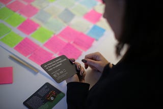 A person holding a black card and reading a question that’s printed on it.