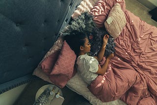 Woman of color asleep in her bed of earth tones
