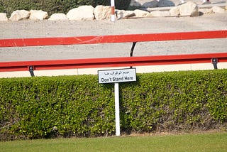 Sign post on the edge of a camel race track outside of Dubai, UAE, that reads “Don’t Stand Here.”